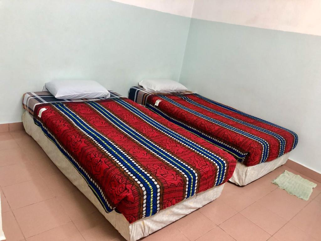 a bed with a colorful blanket on it in a room at Baba's Guest House By The Sea in Batu Ferringhi