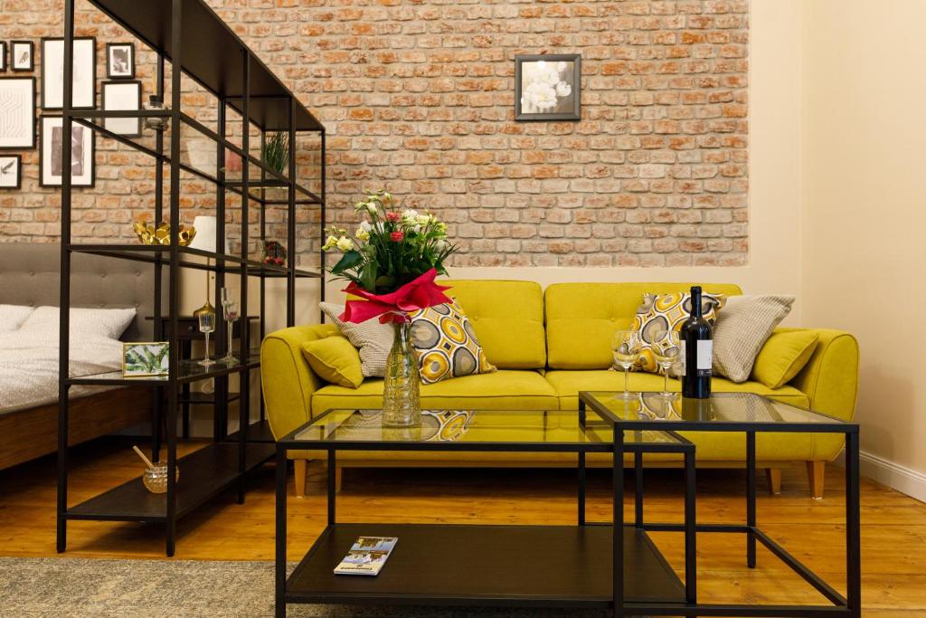 a living room with a yellow couch and a brick wall at Stylish Flat in the Heart of Historical Center in Timişoara