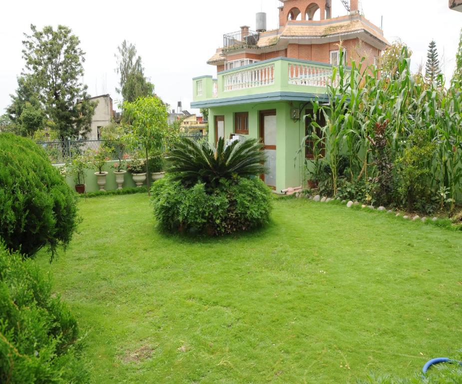 una casa con un césped verde delante de ella en Eco Homestay, en Katmandú