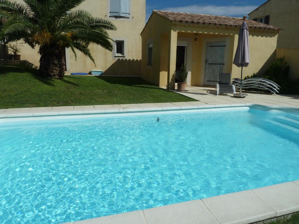uma grande piscina azul em frente a uma casa em Chambre d'hôtes Les Boutons d'Or em Saint-Chamas