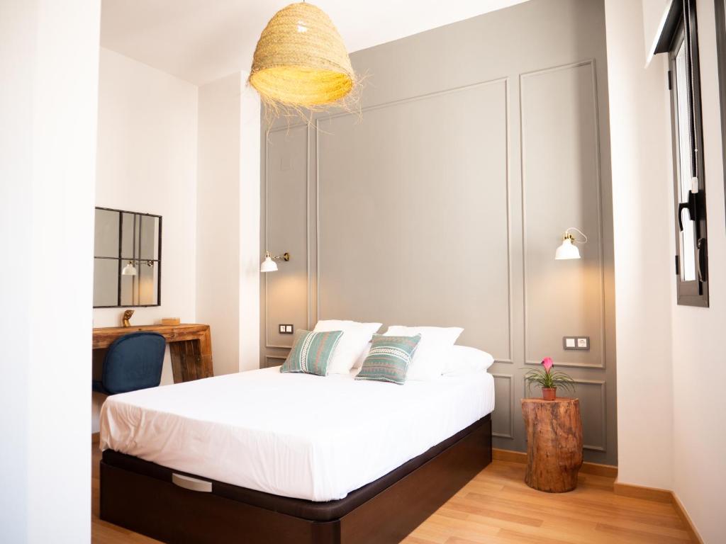 sypialnia z łóżkiem z białymi prześcieradłami i poduszkami w obiekcie Stylish Apartment in the heart of Málaga with Pool w Maladze