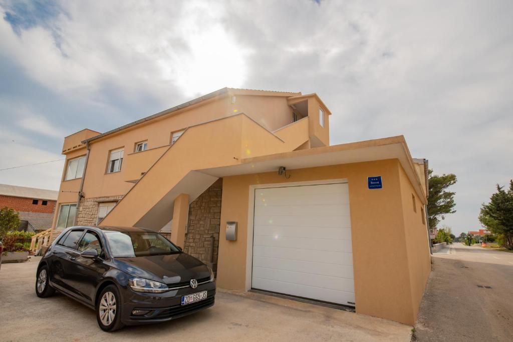 a car parked in front of a house with a garage at Apartman Eva in Vrsi