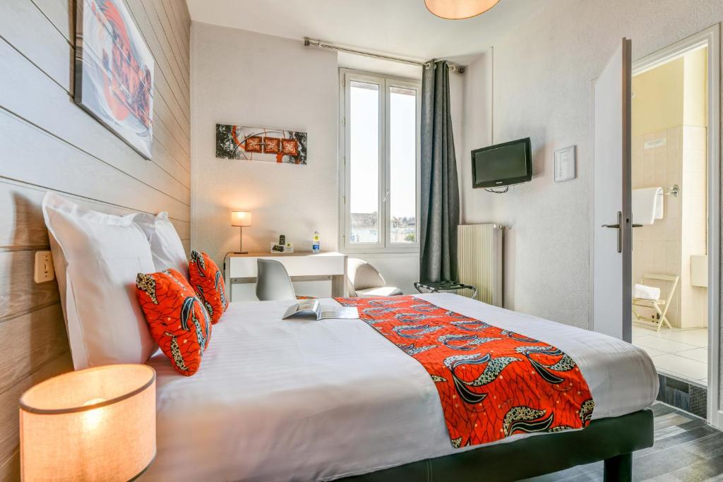 a bedroom with a large bed with orange pillows at Logis Hostellerie du Neez in Gan