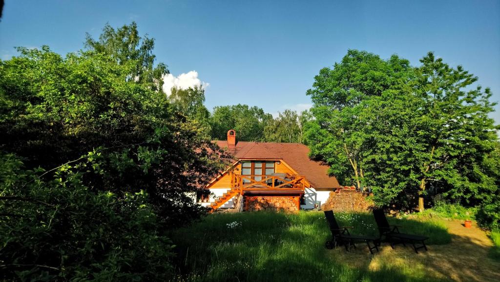 a house with two benches sitting in the grass at Forest Romantic Apartment Brdy in Věšín