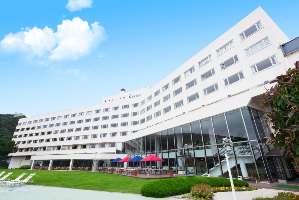 un gran hotel blanco con mesas fuera de él en Hotel Izukyu, en Shimoda