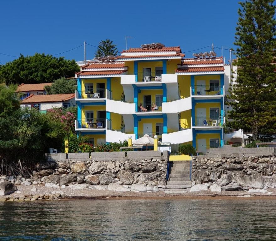 un edificio amarillo y azul junto al agua en Iris Apartments, en Chrani