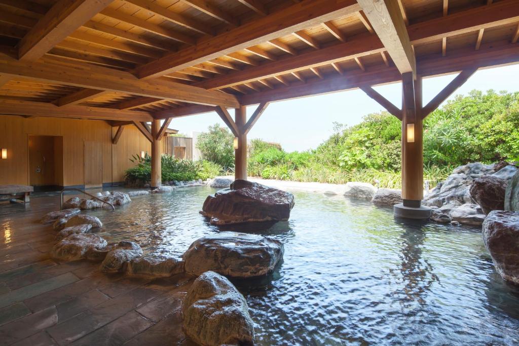 a swimming pool with rocks in the middle of a house at Hotel Izukyu in Shimoda