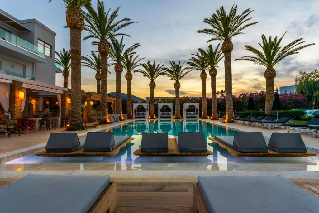 een zwembad met palmbomen en ligstoelen bij Drossia Palms Hotel and Nisos Beach Suites in Malia