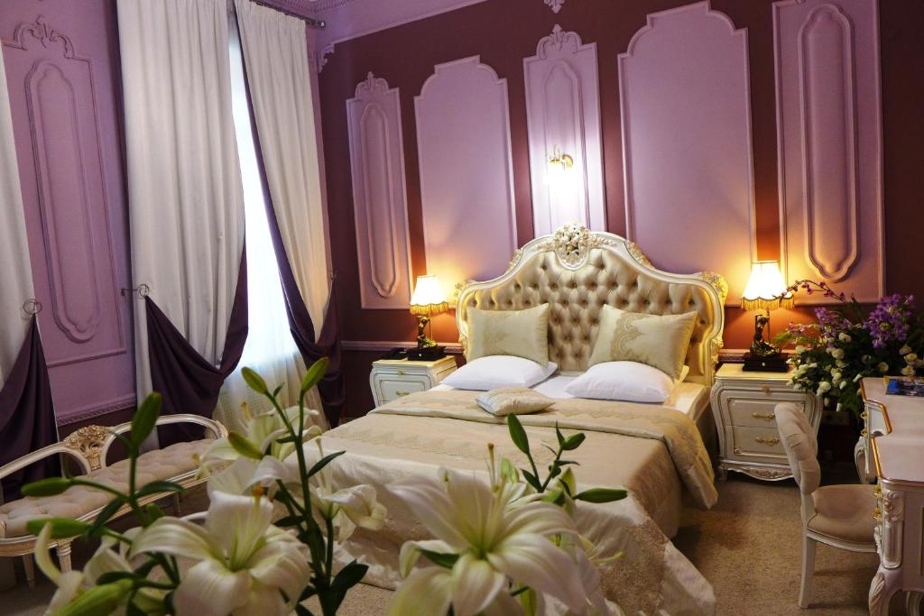 1 dormitorio con 1 cama con paredes y flores púrpuras en Prestige Hotel, en Krasnodar
