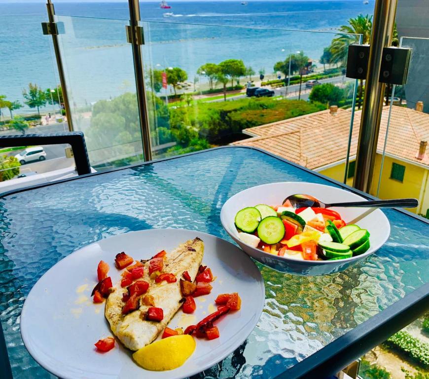 uma mesa com dois pratos de comida e uma tigela de salada em Thalassa Sea View Suite em Limassol