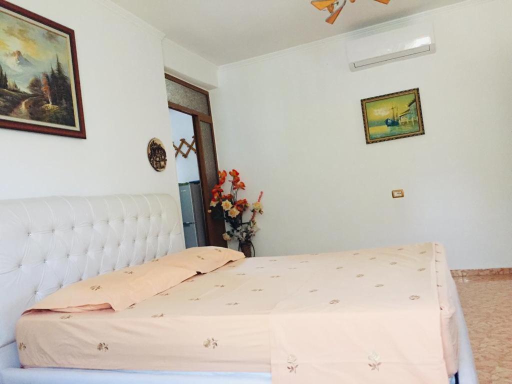 a bedroom with a white bed with a white headboard at Jemin Apartment in Berat