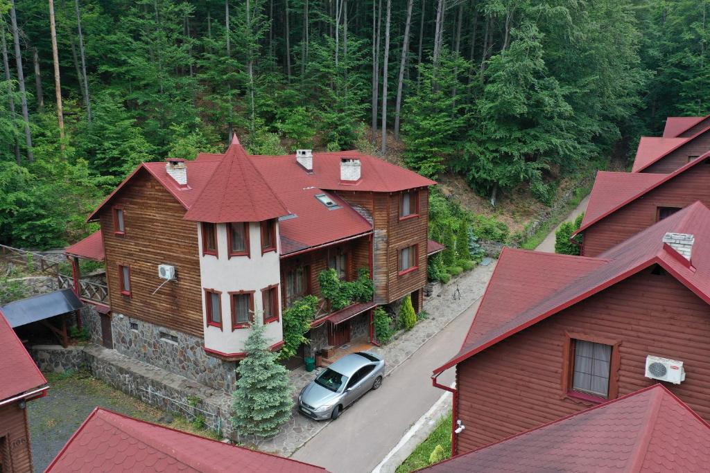 une voiture garée devant une maison aux toits rouges dans l'établissement Elf-cottage, à Turʼya Paseka