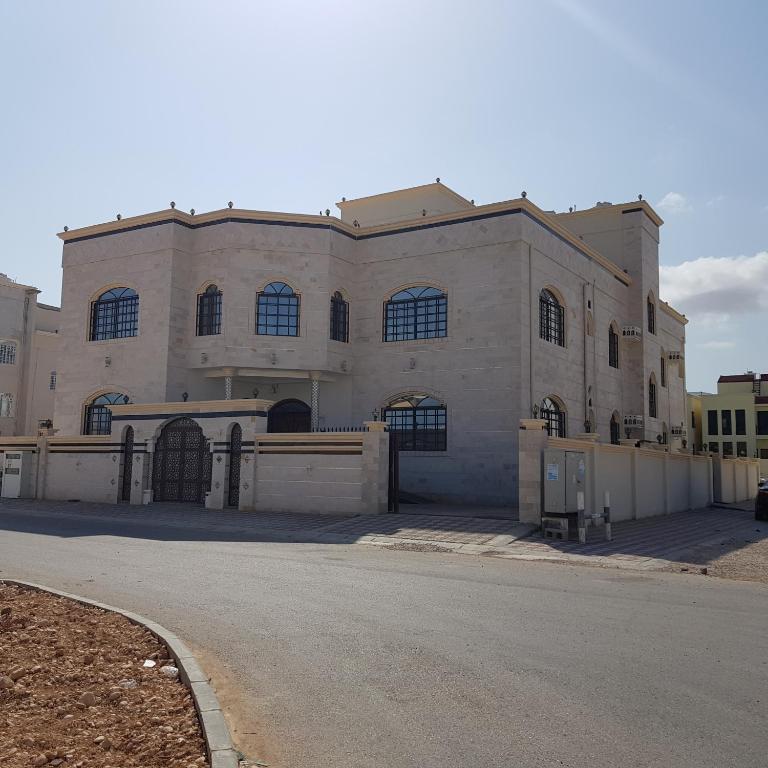a large stone building with a fence in front of it at Alarbee Aljeded in Salalah