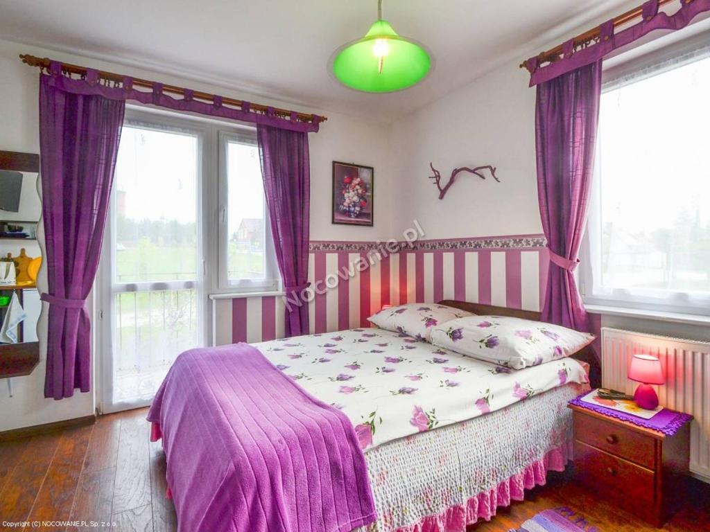 ヤロスワビエツにあるAnna Misiuk pokojeのベッドルーム(紫色のカーテン付きのベッド1台付)