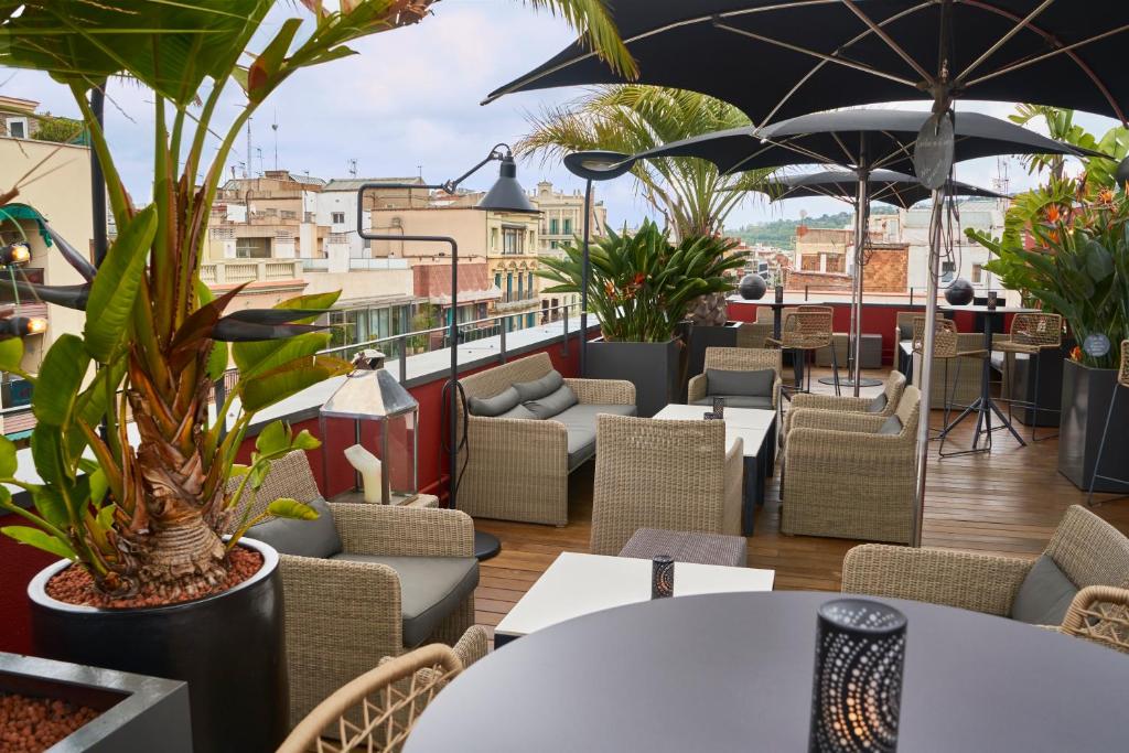 ein Restaurant mit Tischen, Stühlen und Pflanzen auf einem Balkon in der Unterkunft Hotel Villa Emilia in Barcelona