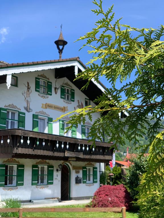 Un grand bâtiment blanc avec volets verts dans l'établissement Haus Gasserer, à Berchtesgaden