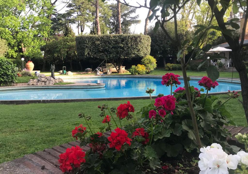 un jardin avec des fleurs rouges et blanches et une piscine dans l'établissement Villa Albina, à Rome