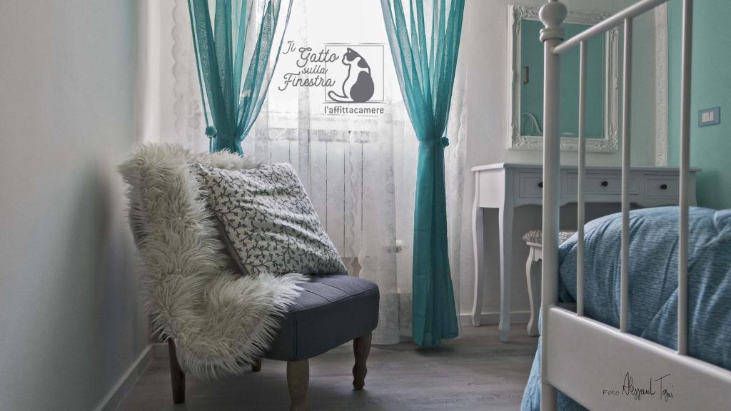 耶西的住宿－Il Gatto Sulla Finestra，一间卧室配有椅子和一张带绿色窗帘的床