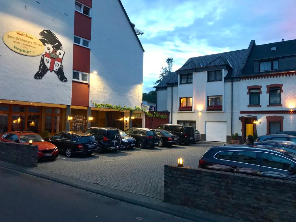 un parcheggio con auto parcheggiate di fronte a un edificio di Hotel & Weinhaus Zum Schwarzen Bären a Coblenza