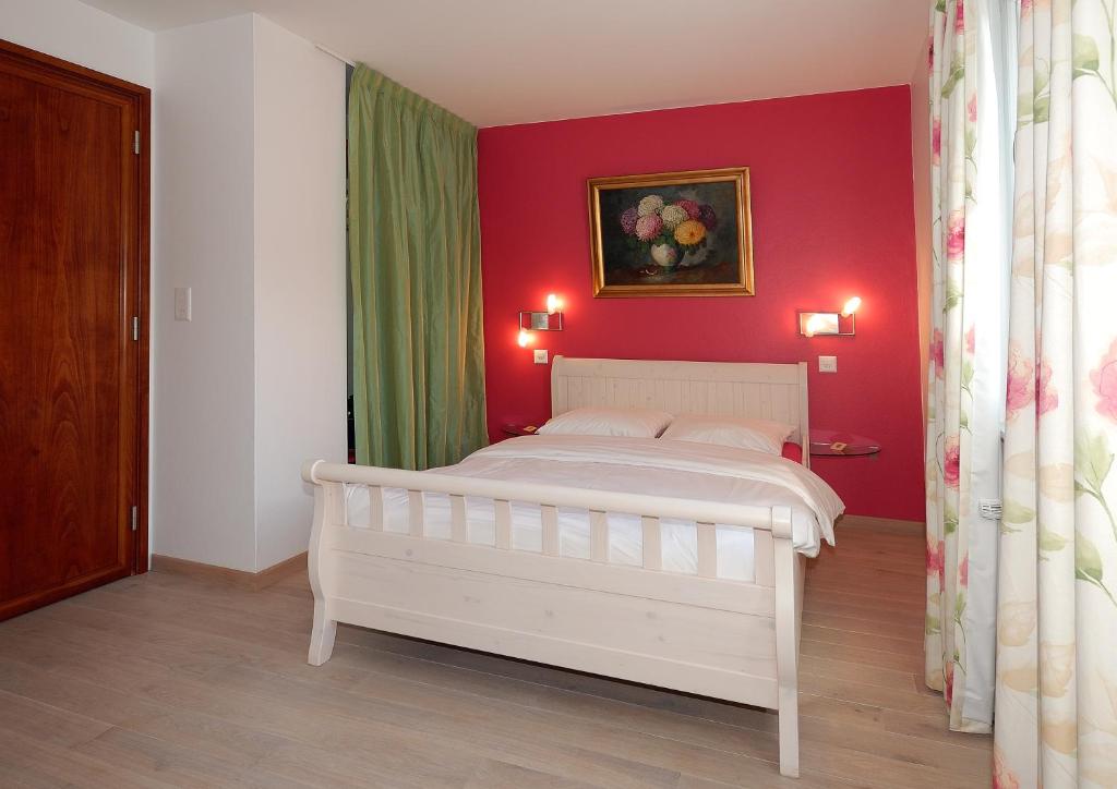 a bedroom with a white bed and a red wall at Auberge de Dully in Dully
