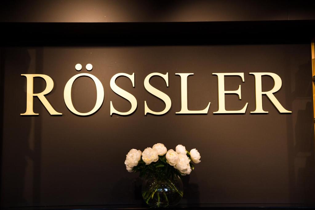 a vase of white flowers in front of a sign at Gästehaus Rössler in Brannenburg