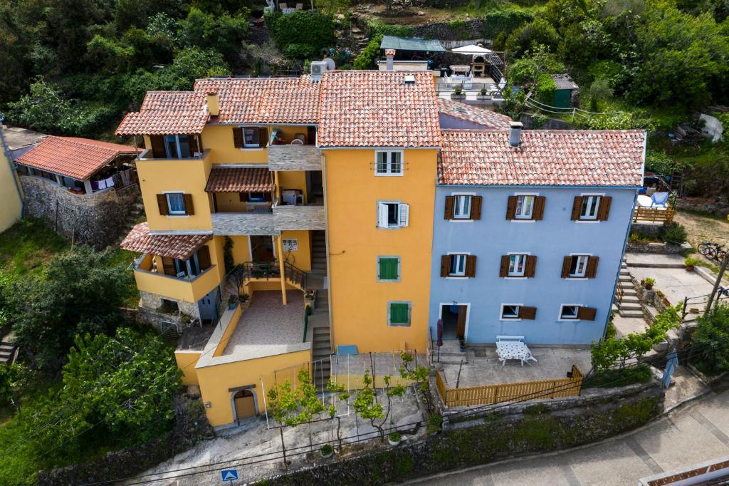 an aerial view of a yellow house with red roof at Apartments and rooms Roberto B. in Valun