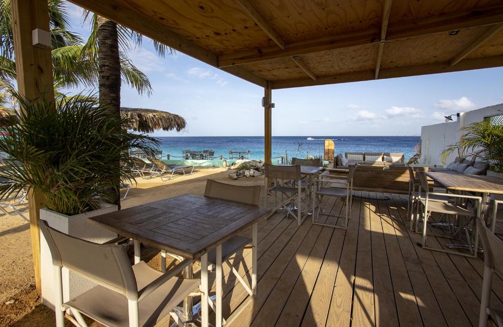 una terraza con mesa y sillas en la playa en Apartment Donkey at Windsock Beach, en Kralendijk