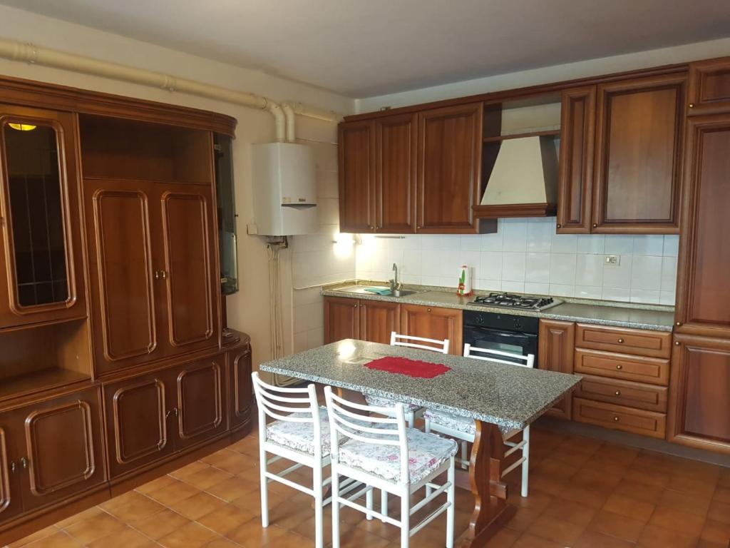 a kitchen with wooden cabinets and a table with chairs at Casa Cippilippi in Saint Vincent