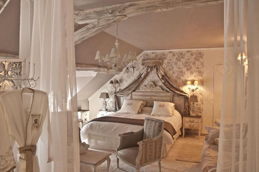 een slaapkamer met een groot bed en een stoel bij La Bergerie des Anges in Le Bignon-Mirabeau