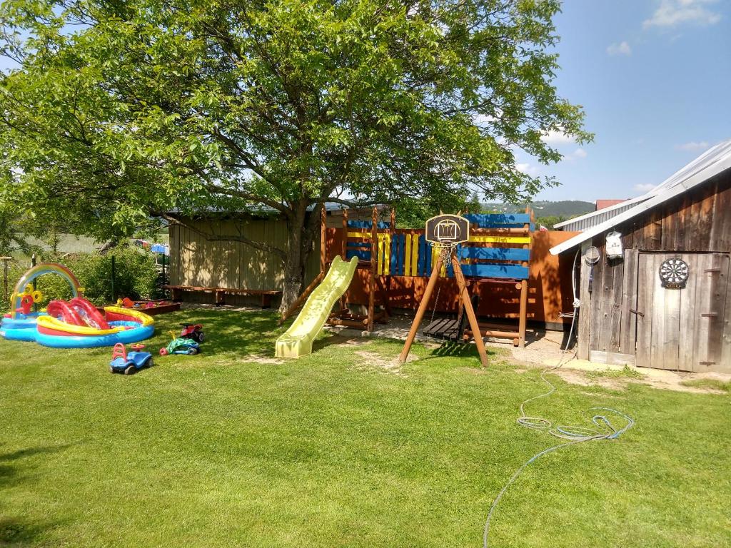 une cour avec une aire de jeux dotée de toboggans et d'un arbre dans l'établissement Pokoje Rożnów, à Rożnów