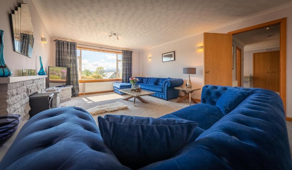 ein Wohnzimmer mit einem blauen Sofa und einem Kamin in der Unterkunft Cairnmhor in Portree