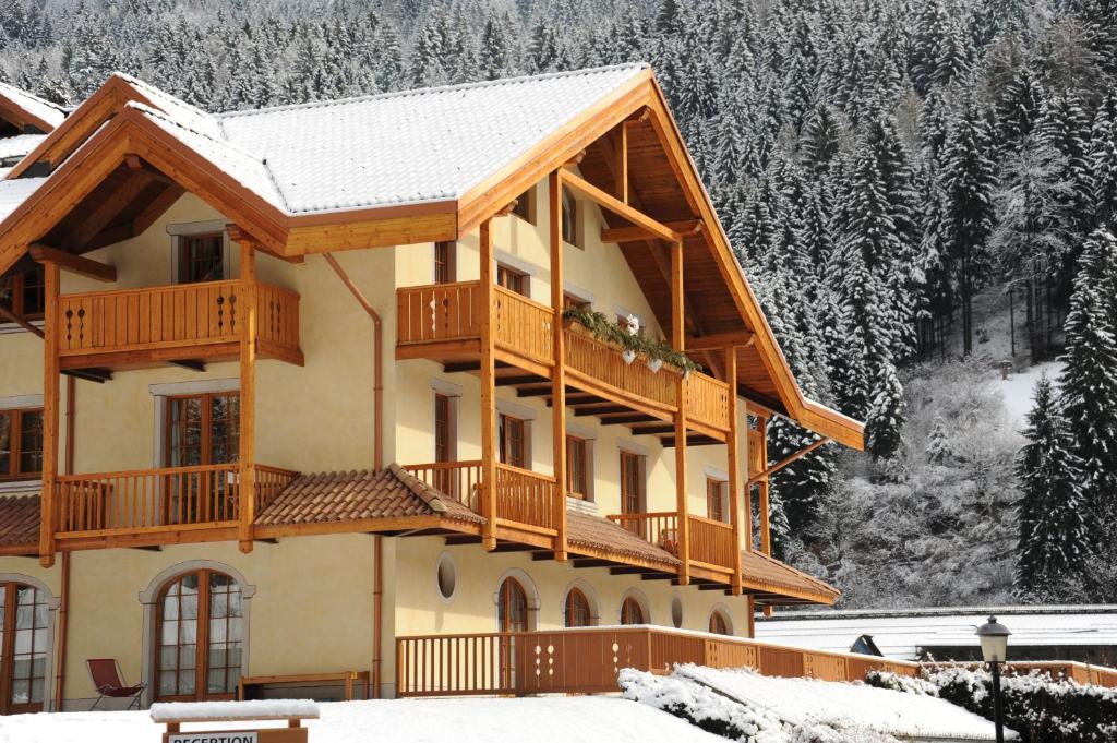a large house with a balcony in the snow at Holidays Dolomiti Apartment Resort in Carisolo