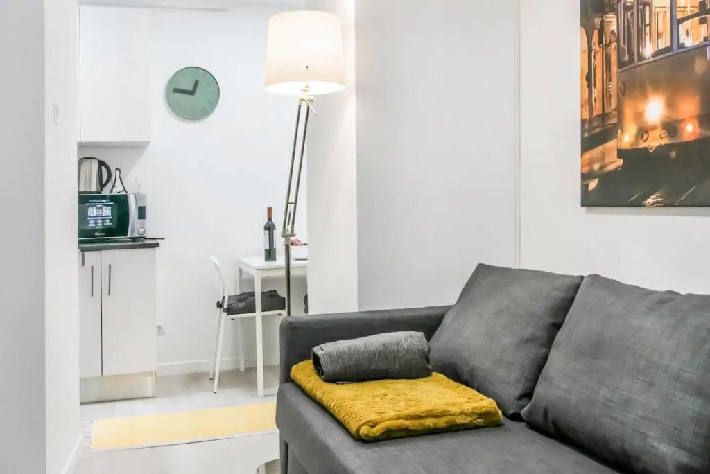 sala de estar con sofá gris y almohada amarilla en HOME4U - Secret Studio in City Center, en Lisboa