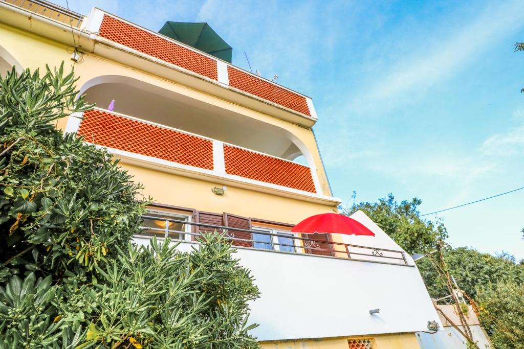 a building with a red umbrella on a balcony at Apartments Andrea in Baška