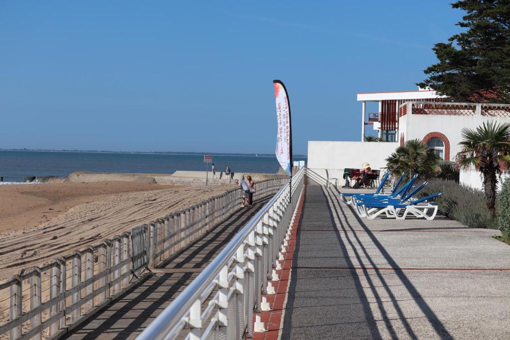 una persona che cammina su un marciapiede accanto alla spiaggia di Residence de L'Ocean a La Tranche-sur-Mer