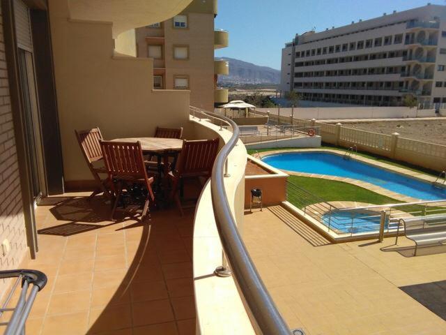 een balkon met een tafel en stoelen en een zwembad bij Las salinas Roquetas de Mar in Roquetas de Mar
