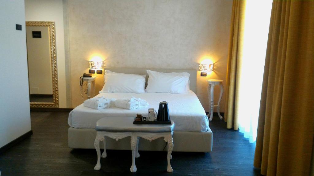 a bedroom with a large white bed with a table at Fantinello Hotel in Caorle