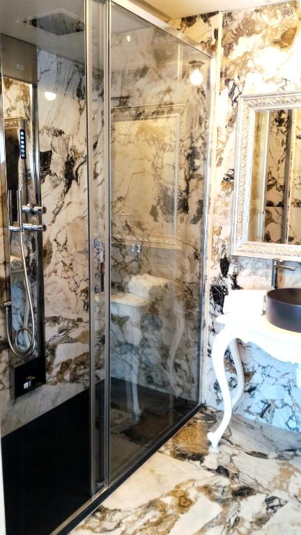 a marble bathroom with a shower and a sink at Fantinello Hotel in Caorle
