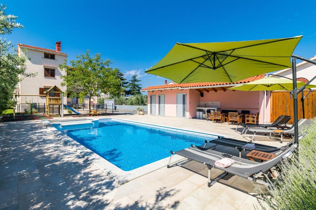 a swimming pool with two chairs and an umbrella at Apartment Anton, Fazana in Fažana