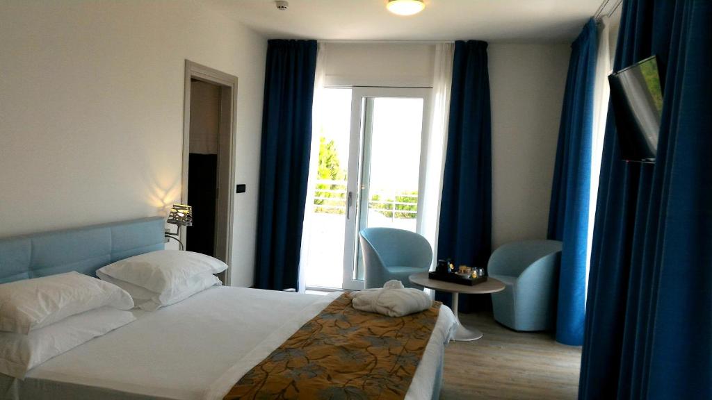 a bedroom with a bed and a window with blue curtains at Fantinello Hotel in Caorle