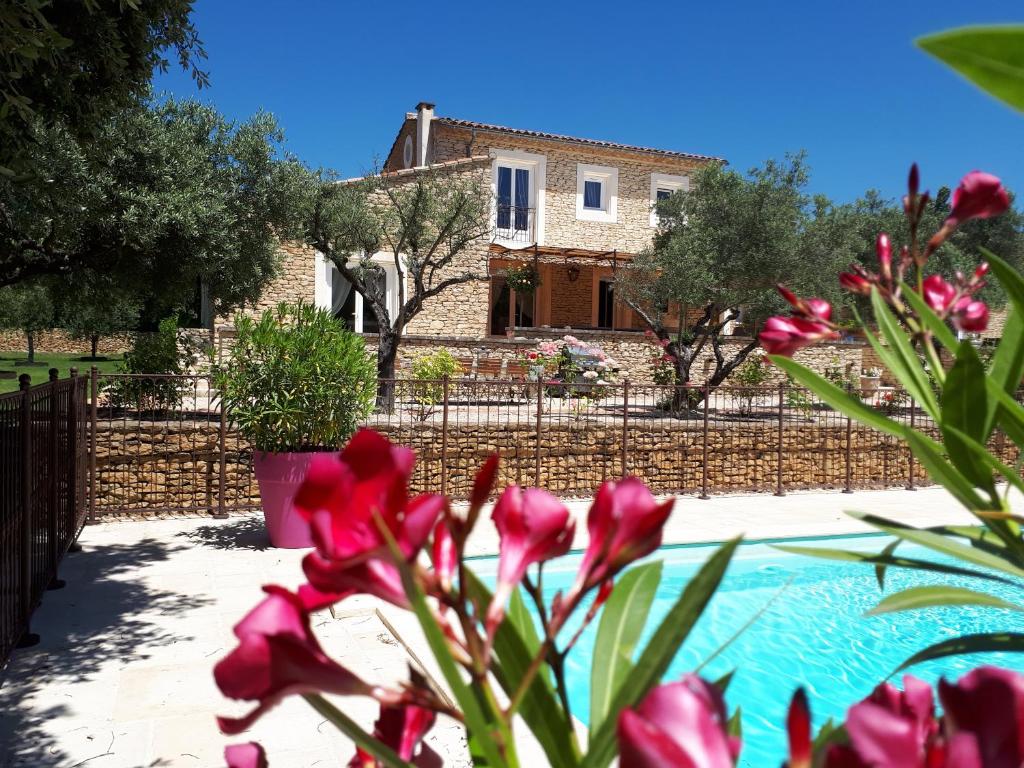 a house in the background with pink flowers in the foreground at la réveuse in Gordes