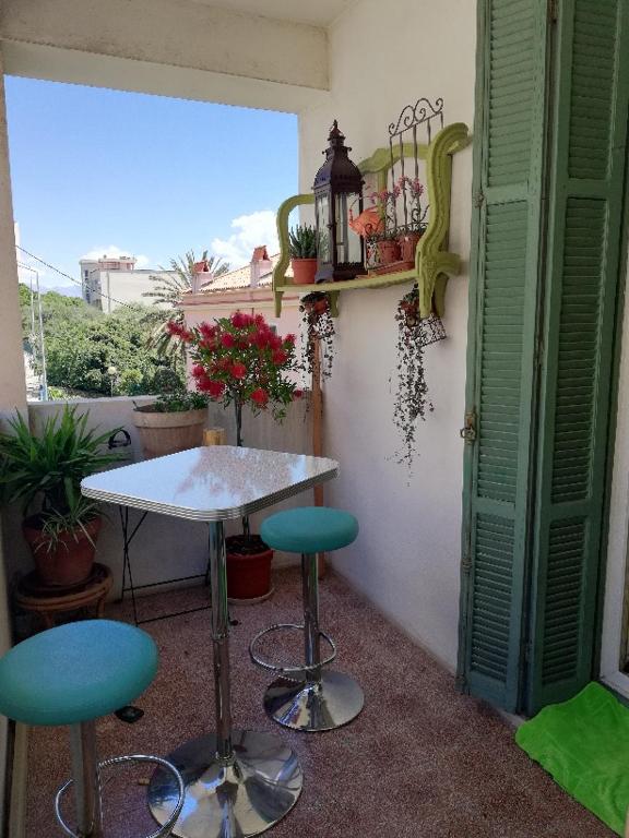 - une table et deux tabourets dans une pièce avec fenêtre dans l'établissement Villa Cécile, à Ajaccio