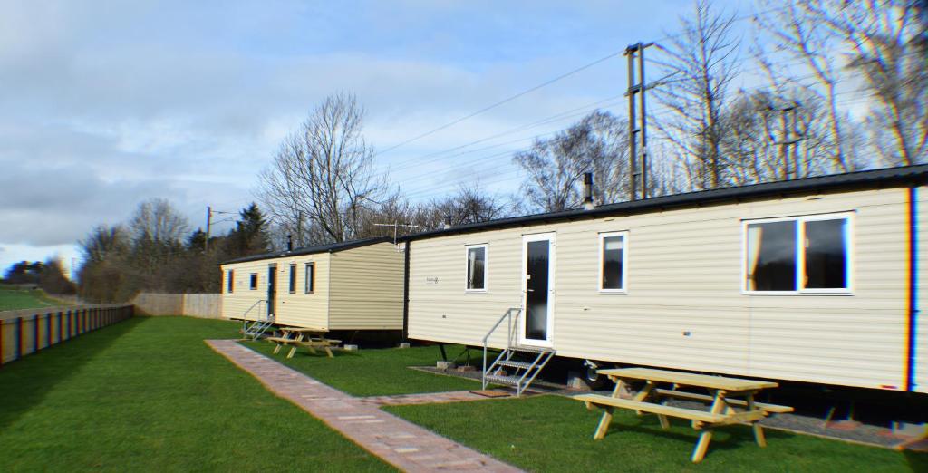 a white trailer with a picnic table and a bench at Chapel View Caravans in Embleton