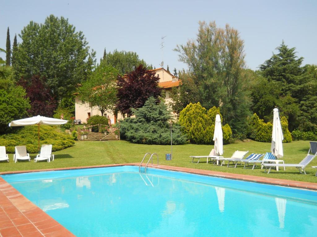 a swimming pool in a yard with chairs and umbrellas at Agriturismo Girasole in Gambassi Terme