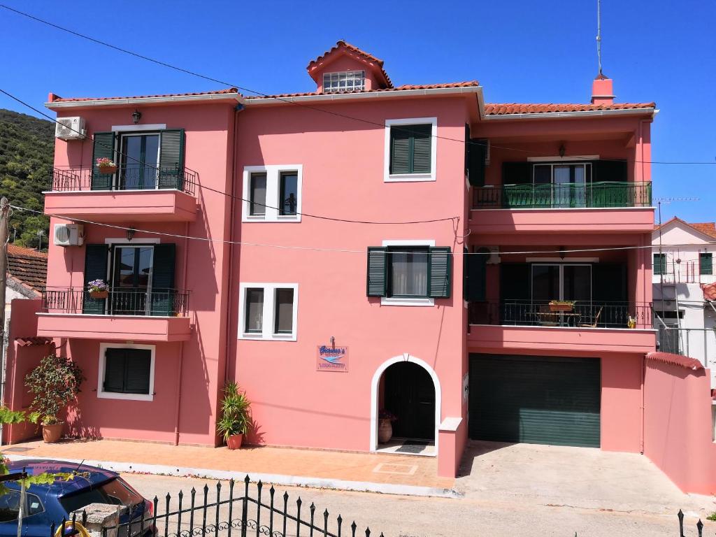 una casa rosa con una recinzione di fronte di Giannos Apartments a Ayia Evfimia