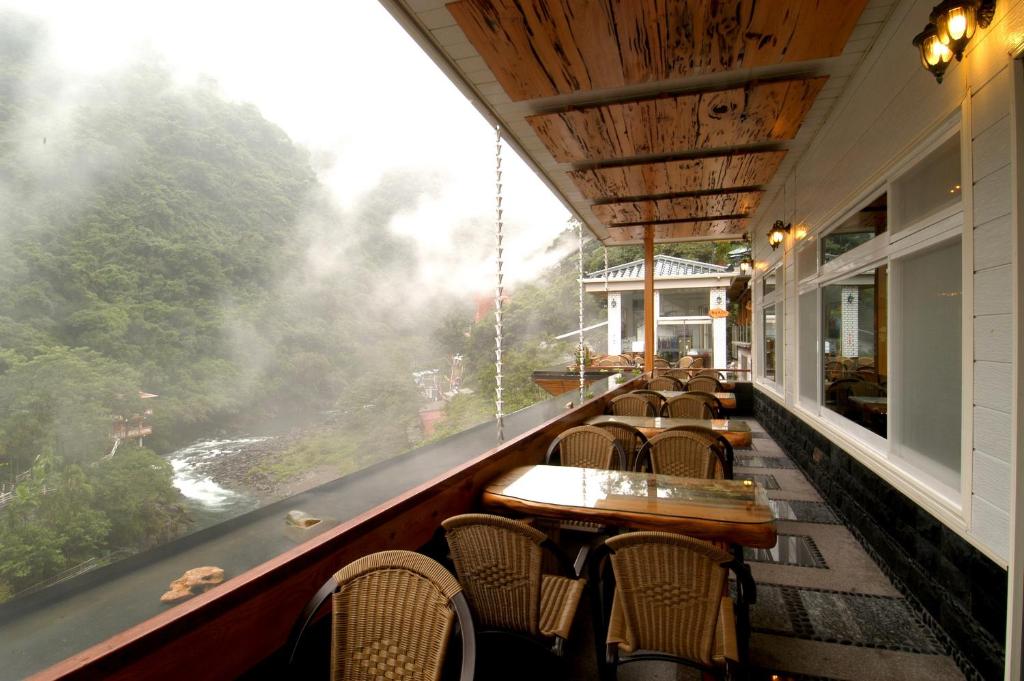 a restaurant with tables and chairs and a view of a river at Full Moon Spa in Wulai