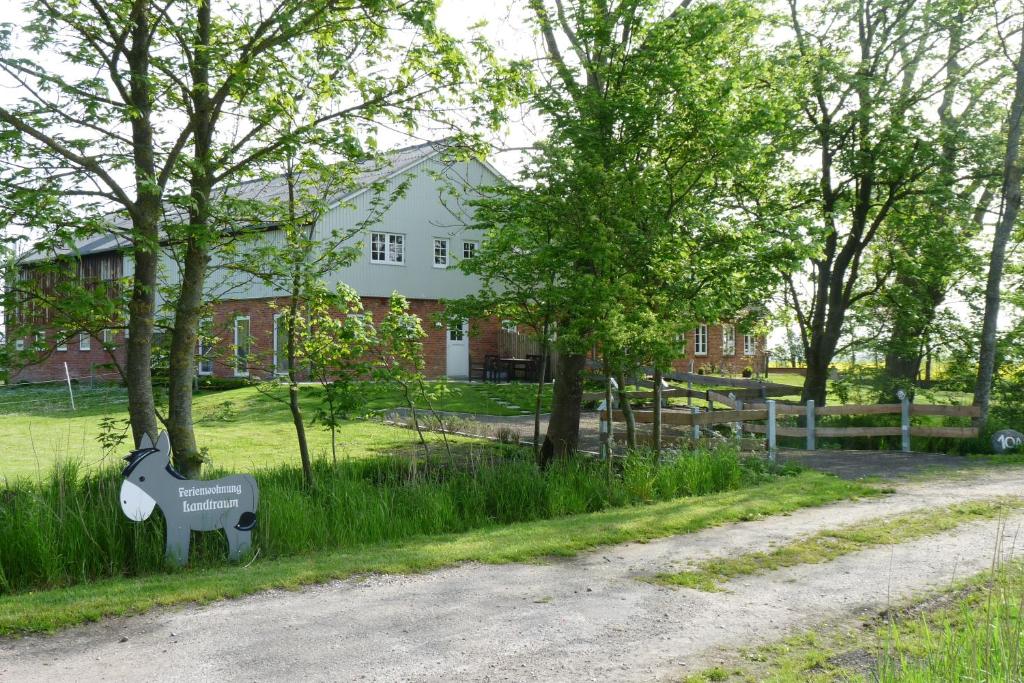 a house with a sign on the side of a road at Ferienwohnung Landtraum in Klanxbüll