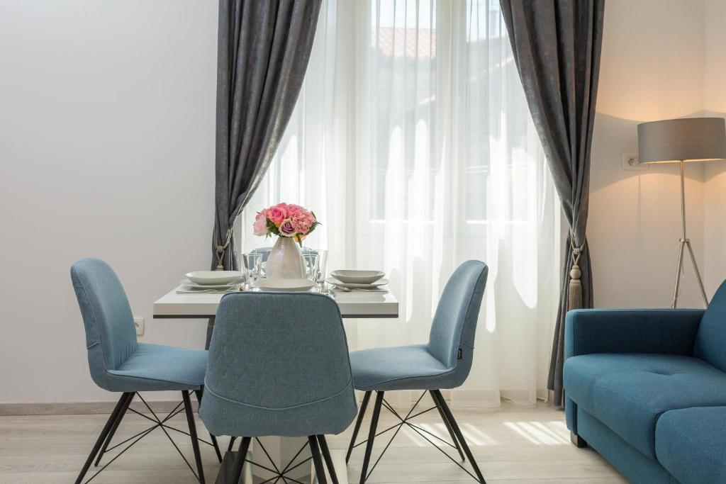 une table à manger avec des chaises bleues et un vase de fleurs dans l'établissement Luxury Studios & Rooms Seven, à Split