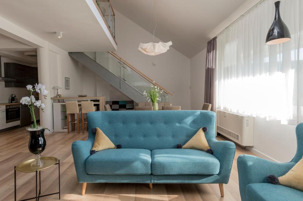 a living room with a blue couch and two chairs at Millennium apartments in Čakovec