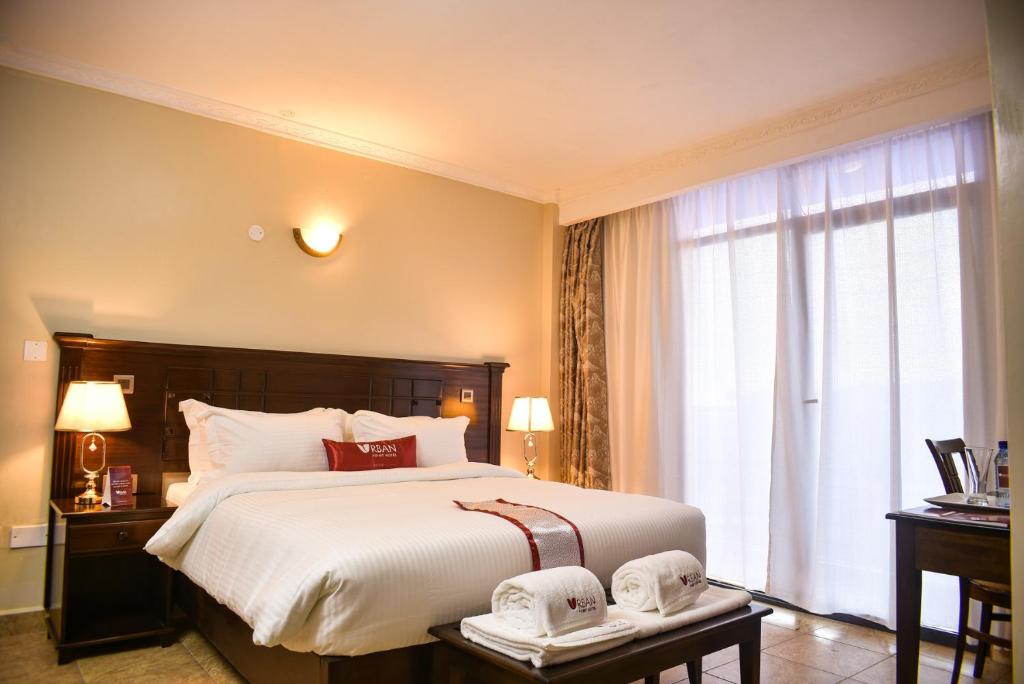 a bedroom with a large bed and a large window at Urban Point Hotel in Nairobi